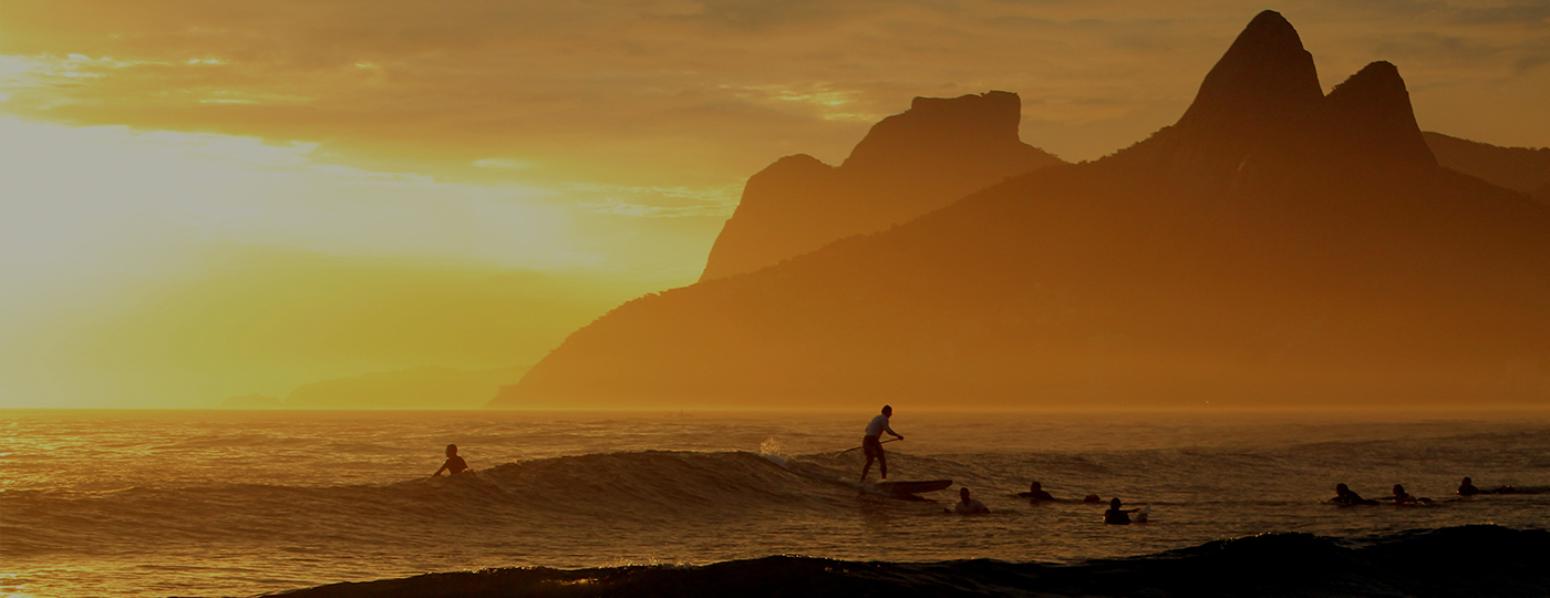 Por do sol em Ipanema com pessoas no mar praticando surf e stand up paddle